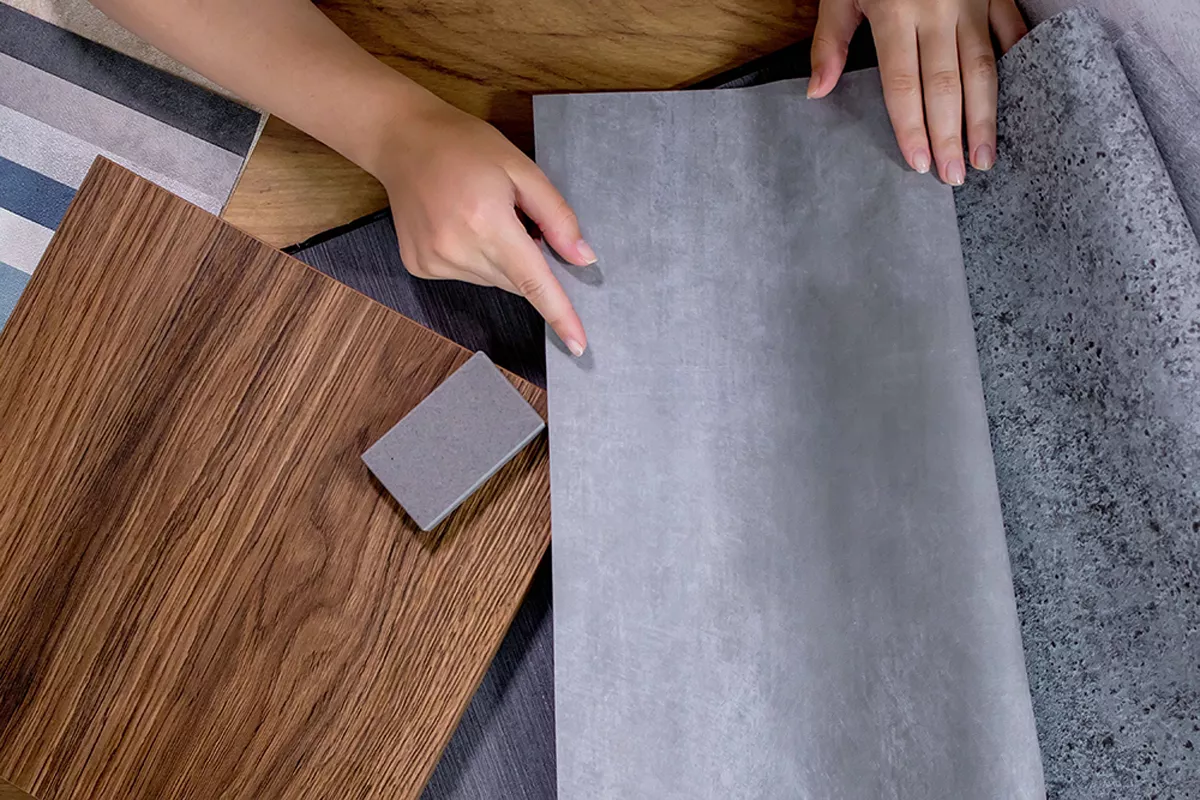 Dieses Bild zeigt eine Person bei der Auswahl und Betrachtung eines Bodenbelags in Vinyl